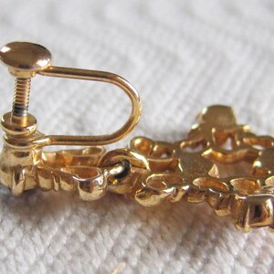 May include: Gold tone clip-on earrings with a floral design. The earrings have a screw-back closure.