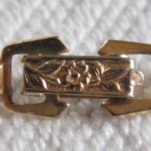 May include: A gold chain bracelet with a detailed floral clasp.
