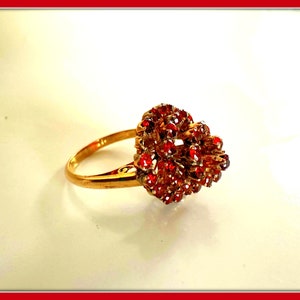May include: A gold ring with a cluster of red gemstones set in a heart shape.