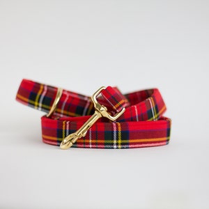 May include: Red and black tartan dog lead with a gold metal clip.