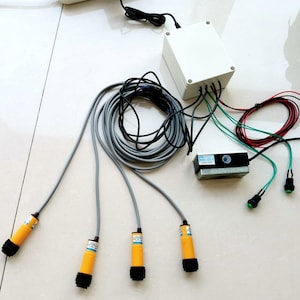 May include: A set of four yellow and black sensor probes with grey cables connected to a white box with a black power cord. The box is connected to a grey and black solenoid valve with a green and black push button switch.