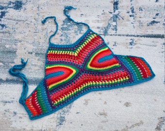 May include: A colorful, handmade crochet top featuring a rainbow of colors including red, orange, yellow, green, blue, and purple. The top has a halter neck design with blue ties and a unique openwork pattern.