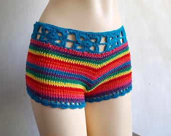 May include: Rainbow crochet shorts with a blue crocheted waistband. The shorts have a scalloped edge and a floral design on the waistband.