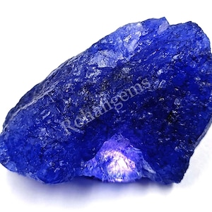 Può includere: Una grande gemma blu grezza con un colore profondo e ricco. La gemma ha un aspetto naturale non levigato ed è un bellissimo esempio di cristallo grezzo.