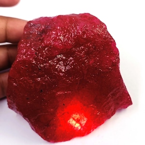 May include: A white ceramic mug with a black handle and the text "But First, Coffee" in a bold, black font. The mug is set against a blurred background, suggesting a cozy setting.