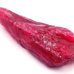 Puede incluir: Un gran cristal de rubí rojo áspero con un extremo puntiagudo. El cristal tiene un color rojo intenso y rico y un acabado brillante.