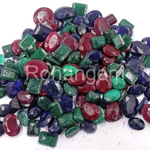 May include: A collection of gemstones in various shapes and sizes, including oval, emerald cut, and round. The gemstones are in shades of red, green, and blue. The text "Rohangems" is visible on some of the gemstones.