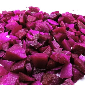 Puede incluir: Primer plano de un montón de trozos de remolacha de color morado oscuro, probablemente para una ensalada u otro plato.