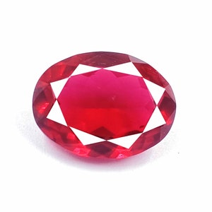 May include: A deep red oval-shaped gemstone with a faceted cut.