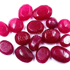 May include: A collection of 14 oval-shaped, faceted, pink gemstones. The gemstones are smooth and polished, with a slight sheen.