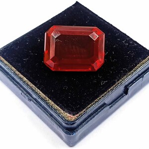 Peut inclure: Une pierre pr&eacute;cieuse rouge de forme rectangulaire, pos&eacute;e dans un &eacute;crin en velours noir.