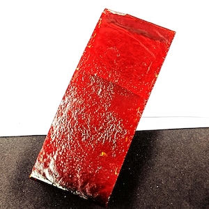Può includere: Un oggetto rettangolare rosso con una superficie strutturata. L'oggetto ha una finitura lucida e sembra essere fatto di un materiale solido. Il colore è un rosso intenso e vibrante.