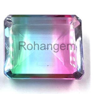 May include: A rectangular gemstone with a gradient of colors, including green, blue, and pink. The gem has a faceted cut and the text "Rohangem" is visible on the surface. The gemstone is set against a white background.