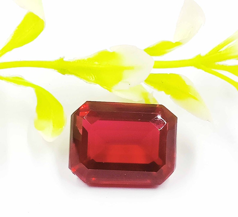 Peut inclure: Une pierre pr&eacute;cieuse de couleur rouge fonc&eacute;, taill&eacute;e en &eacute;meraude, avec un haut poli.