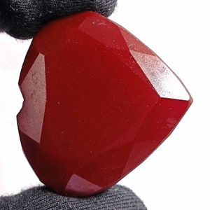 Può includere: Una pietra preziosa di colore rosso intenso a forma di cuore con taglio sfaccettato. La pietra preziosa è lucidata e ha una superficie liscia.