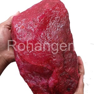 Peut inclure: Une grosse pierre précieuse de rubis rouge brute. Le rubis est d'une couleur rouge foncé et riche et a une finition naturelle non polie.