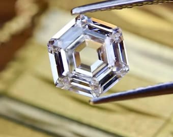 May include: A clear, octagonal-shaped diamond gemstone held by tweezers. The diamond has a unique, stepped cut with multiple facets.