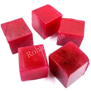 May include: Five red, square-shaped, polished gemstones. The gemstones are smooth and have a slight sheen.