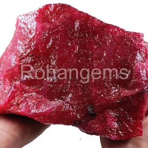 Peut inclure: Une grosse pierre précieuse de rubis rouge brute. Le rubis est d'une couleur rouge foncé et riche et a une surface naturelle non polie.