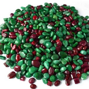 May include: A large pile of loose green and red gemstones. The gemstones are of various shapes and sizes.