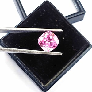 Può includere: Una pietra preziosa rosa a cuscino in una scatola di gioielli in velluto nero.