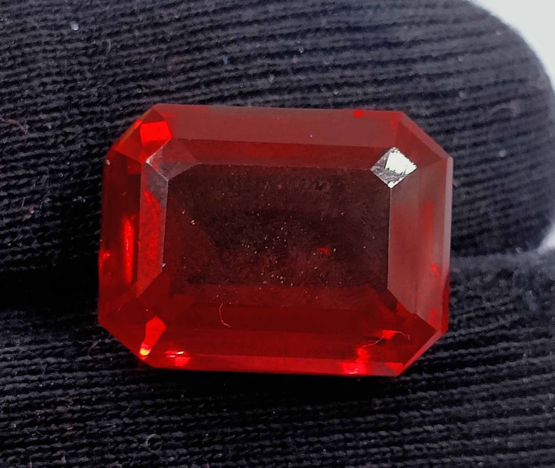 Peut inclure: Une pierre pr&eacute;cieuse de couleur rouge fonc&eacute;, taill&eacute;e en &eacute;meraude, avec un haut poli.