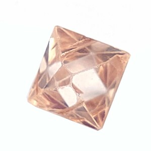 Può includere: Un diamante chiaro, sfaccettato, marrone chiaro di forma quadrata.