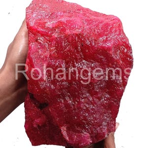 Peut inclure: Une grosse pierre précieuse de rubis rouge brute. Le rubis est d'une couleur rouge foncé et riche et a une finition naturelle non polie.