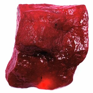 May include: A large, rough, red gemstone with a deep, rich color. The gemstone has a natural, unpolished surface.