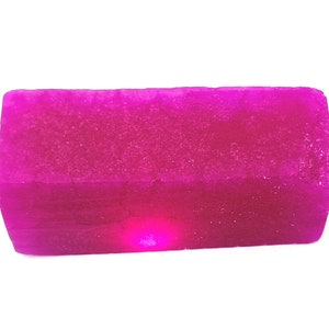 Può includere: Una saponetta rettangolare di colore rosa acceso.