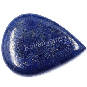 May include: A polished, teardrop-shaped lapis lazuli gemstone. The deep blue stone has gold flecks and the text "Rohangems" on the surface. The gemstone is set against a white background.