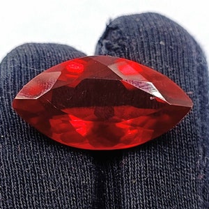 May include: A deep red marquise-shaped gemstone with a faceted cut.