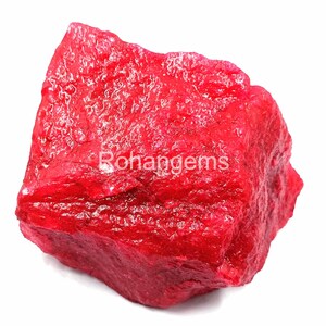 Könnte beinhalten: Ein großer, roher, roter Rubin-Edelstein. Der Rubin hat eine tiefe, satte rote Farbe und eine natürliche, unpolierte Oberfläche.