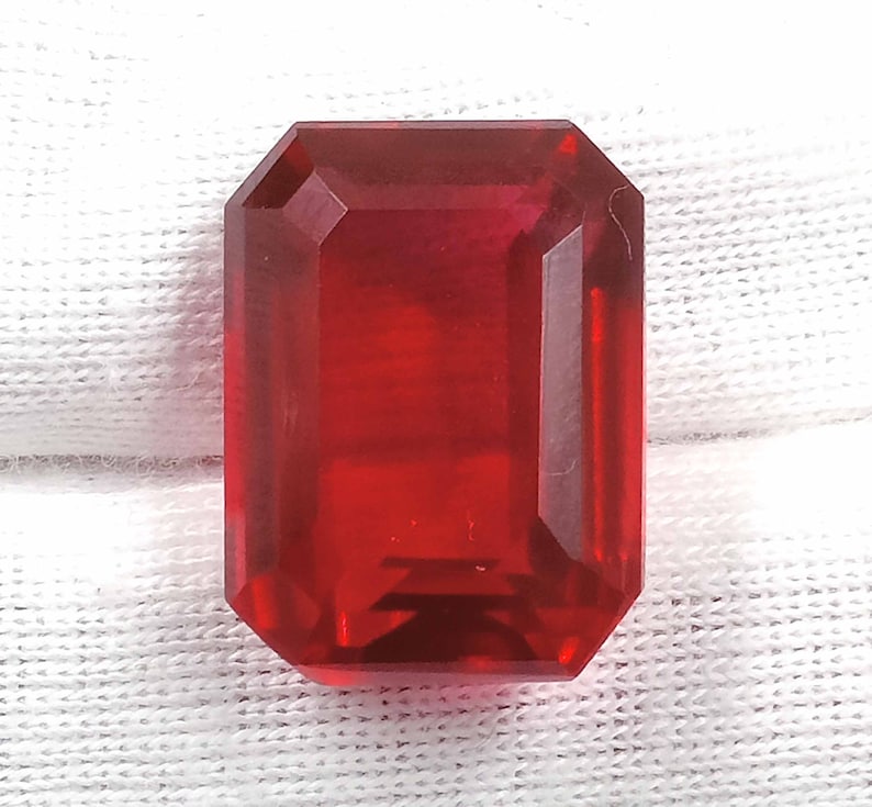 Peut inclure: Une pierre pr&eacute;cieuse de couleur rouge fonc&eacute; taill&eacute;e en &eacute;meraude avec un haut poli.