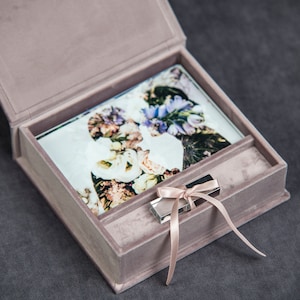 May include: A light pink velvet box with a clear glass insert containing a photograph of a couple. A small silver USB drive with a pink ribbon is in the box.