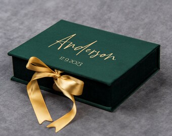 May include: A green velvet box with a gold ribbon and the name "Anderson" and the date "17.9.2023" written in gold lettering.