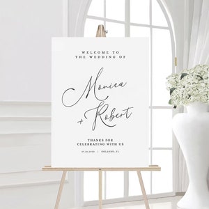 May include: White wedding welcome sign with black text. The sign reads "Welcome to the wedding of Monica + Robert. Thanks for celebrating with us. 07.16.2030 Orlando, FL"