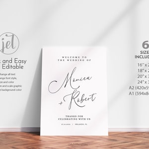 May include: A white wedding welcome sign with black text that reads "Welcome to the wedding of Monica + Robert" with the date "07.14.2030" and location "Orlando, FL". The sign also includes the text "Thanks for celebrating with us".