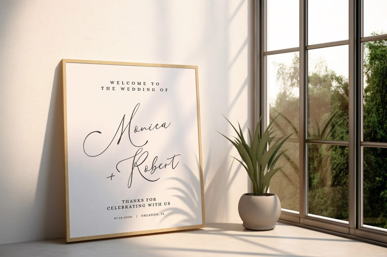 May include: A framed wedding sign with a white background and black text. The sign reads "Welcome to the wedding of Monica + Robert. Thanks for celebrating with us. 03.16.2019 | Orlando, FL."