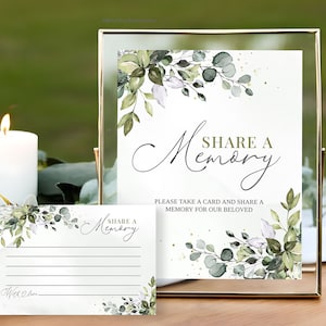 Peut inclure: Une pancarte dor&eacute;e avec un fond blanc et un motif de feuillage vert. La pancarte indique "Partager un souvenir" et "Veuillez prendre une carte et partager un souvenir pour notre bien-aim&eacute;". Il y a une carte plus petite avec le m&ecirc;me motif et le texte "Partager un souvenir".