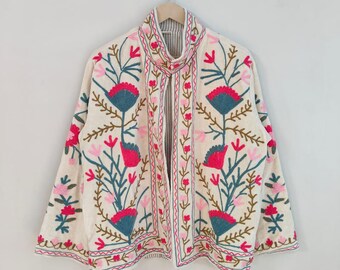 May include: Cream-colored embroidered jacket with a floral design. The jacket features pink, teal, and brown floral embroidery. The jacket is hanging on a wooden hanger against a white background.