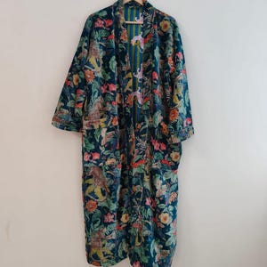 Può includere: Lungo accappatoio in velluto blu scuro con una vivace stampa floreale e animalier. L'accappatoio presenta un collo a scialle, maniche lunghe e una fodera a righe. La stampa comprende fiori, foglie e figure di animali.
