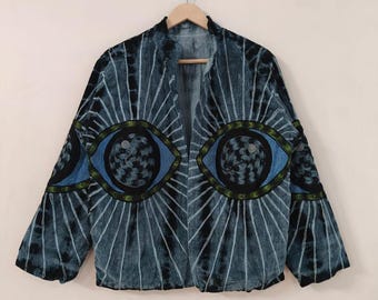 May include: A blue tie-dye jacket with large eye designs on the front. The jacket has a collared neckline and long sleeves. The eye designs are blue, black, and green, with white radiating lines.