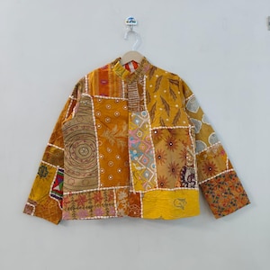 May include: A patchwork jacket in shades of yellow, orange, and brown, with intricate embroidered and patterned fabric squares. The jacket has a mandarin collar and long sleeves, creating a unique and artistic garment.