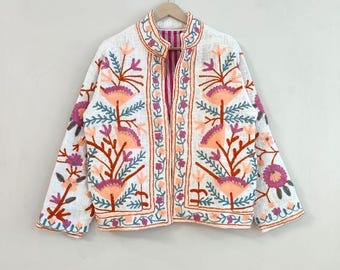 May include: White embroidered jacket with a mandarin collar. The jacket features a floral design in shades of orange, pink, and blue. The interior lining is a striped pink fabric. The jacket is hanging on a wooden hanger.