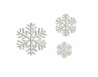 Op de afbeelding: Drie witte borduurmotieven van sneeuwvlokken, de grootste in het midden, de kleinste onderaan.