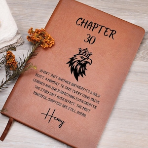 May include: A brown leather journal with the text "CHAPTER 30" and a black eagle illustration. The journal includes the text "30 isn't just another birthday..." and the name "Henry". A bookmark is visible.