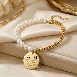 Op de afbeelding: Goudkleurige armband met een parel- en kralenontwerp. De armband heeft een ronde bedel met de tekst "TO MY WIFE" en een liefdevolle boodschap. De armband wordt gepresenteerd op een crèmekleurige satijnen stof.