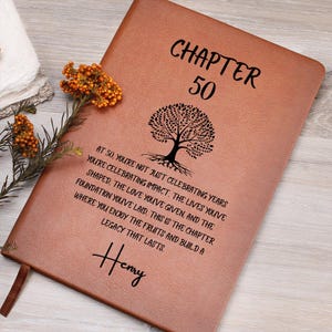 May include: A brown leather journal with the words "CHAPTER 50" and a tree illustration. The journal has a quote about celebrating impact and legacy. The name "Henry" is written at the bottom.