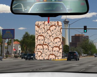 May include: A car air freshener with a pattern of a man's face. The air freshener is beige and brown.